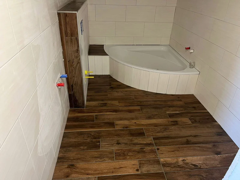 Badezimmer in Scharbeutz mit neuem Fliesenboden in Holzoptik und Eckbadewanne