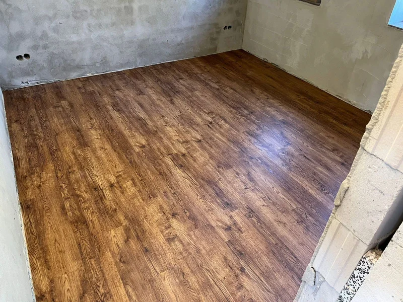Neu verlegter Vinylboden in Holzoptik in Scharbeutz, Raum mit roh verputzten Wänden