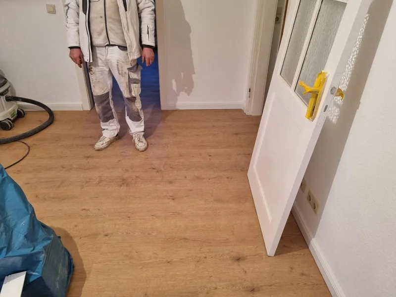 Handwerker verlegt Designboden im Wohnraum nach Brandschadensanierung in Kappeln