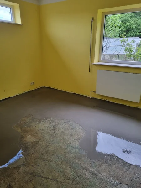 Gelber Wandanstrich und frisch verlegter Fließestrich vor der Bodenverlegung in Kappeln