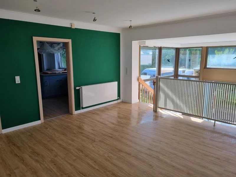 Wohnzimmer mit grünem Wandanstrich und neuem Designboden nach der Sanierung in Kappeln