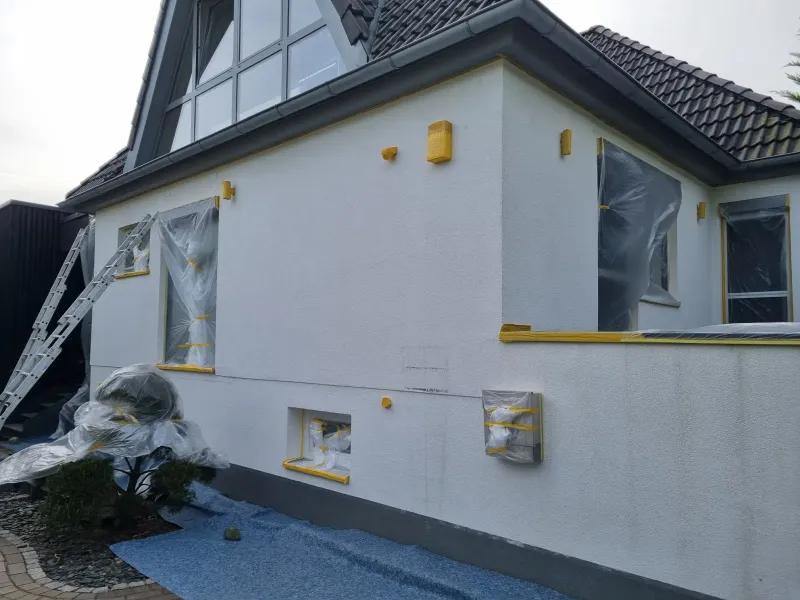 Abgeklebte Fenster und Kanten als Vorbereitung für den Fassadenanstrich
