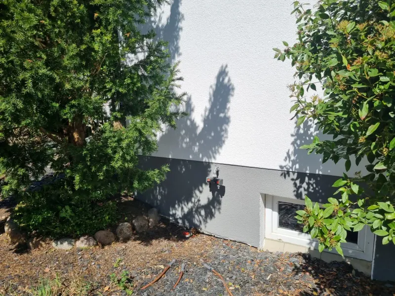 Hausecke mit zweifarbig gestrichener Fassade und Kellerfenster