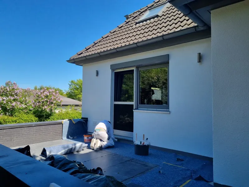 Handwerker bei Abdichtungsarbeiten auf einer Terrasse im Rahmen einer Fassadensanierung