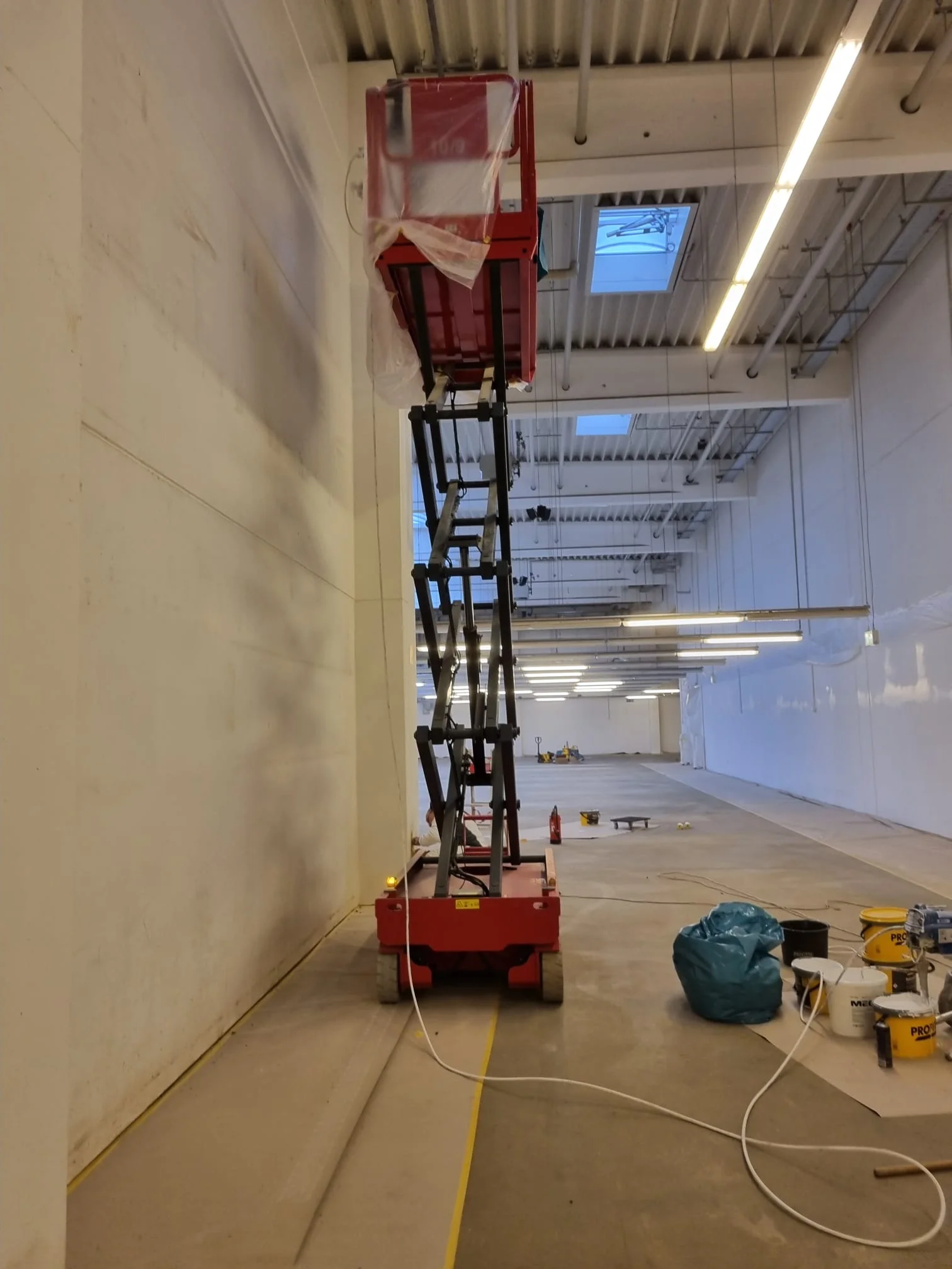 Hebebühne im Einsatz für Wandspritzarbeiten in großer Höhe, Lagerhalle Gönnebek