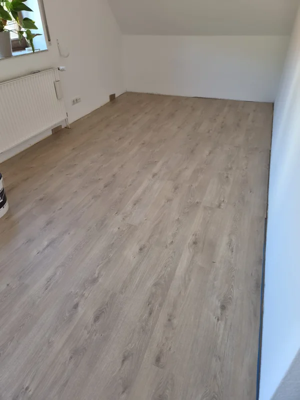 Zimmer unter der Dachschräge, der Laminatboden ist verlegt, die Sockelleisten stehen noch aus