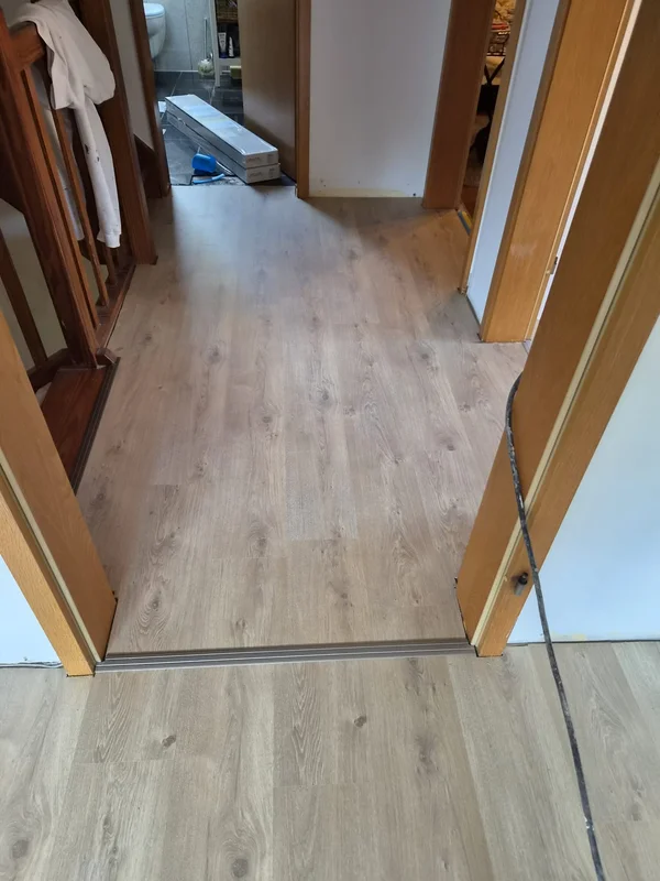 Blick vom neu verlegten Boden in Richtung Bad, wo Fliesen und Sanitärobjekte bereits fertig sind