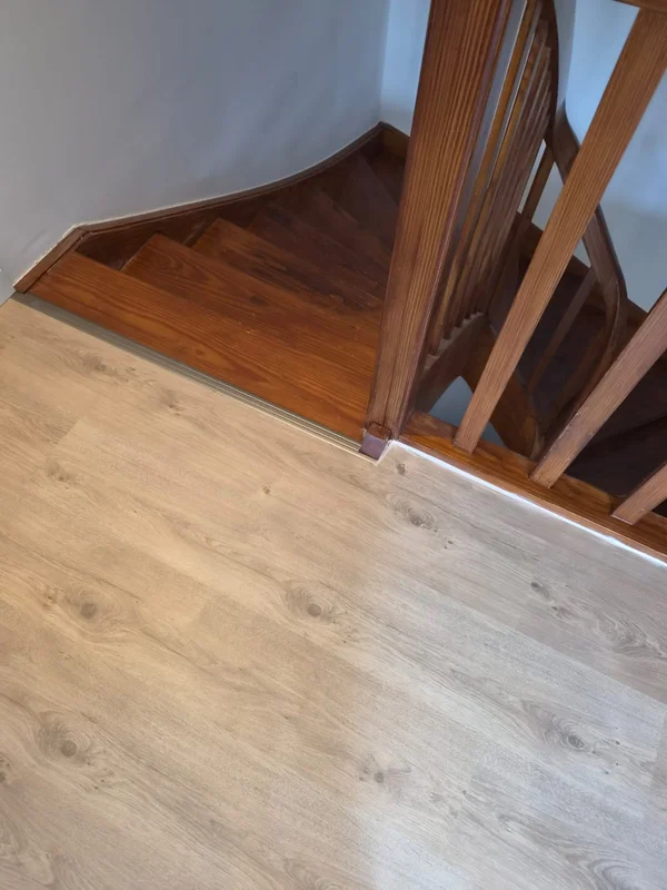 Am Fuß der alten Holztreppe trifft das neue Laminat auf eine Abschlussschiene, die den Höhenunterschied sauber ausgleicht
