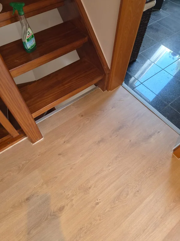 Treppenbereich mit dem neuen Laminat und Blick durch eine Glastür auf den gefliesten Bereich dahinter