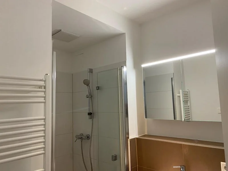 Frisch gestrichenes Badezimmer mit Dusche und Spiegel