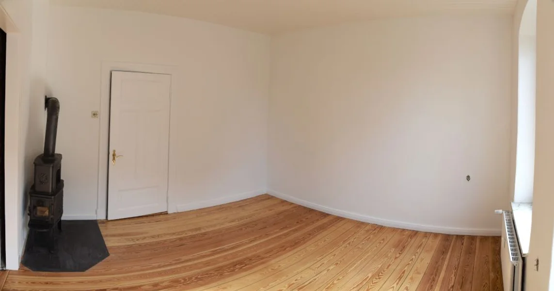 Zimmer mit Kaminofen und weißer Tür, frisch gestrichene Wände
